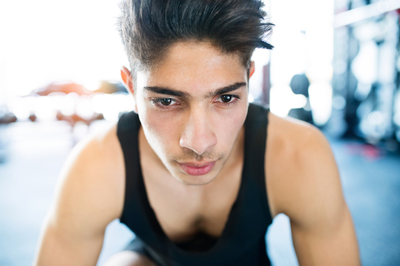 Young fit hispanic man in black sleeveless shirt in gym
