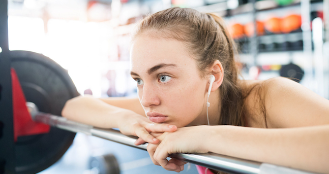 Young woman in gym, earphones in her ears,listening music